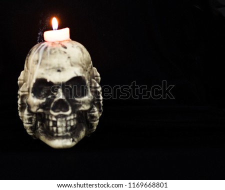 Blurry picture of skull with white candle and candle light with copy space for Halloween