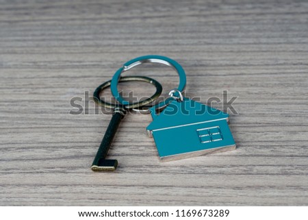 key and house shape key tag on wooden table. home security and buying house concept