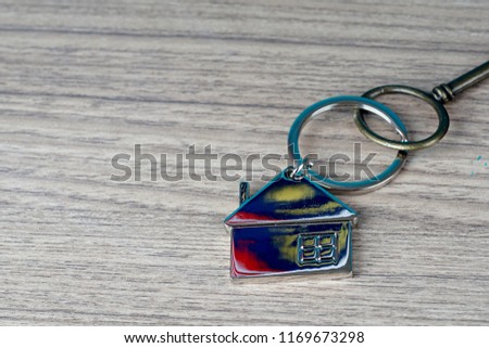 key and house shape key tag on wooden table. home security and buying house concept