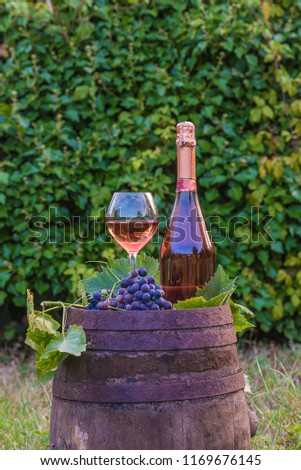 Bottle and glass of pink champagne on old barrel oudtoors, vertical picture