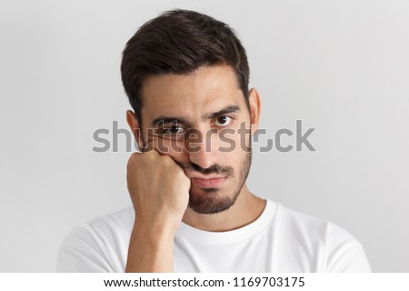 Closeup photo of young caucasian man isolated on gray background dressed casually, pressing hand to chin. looking bored, exhausted and disappointed, feeling helpless and upset, facing problems Royalty-Free Stock Photo #1169703175