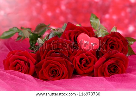 Beautiful bouquet of roses on pink fabric on red background