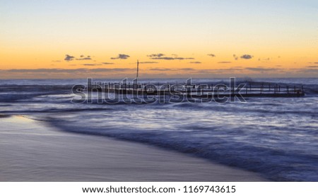 colourful image of rock pool with twilight around sunrise and beach in foreground and sky in background
