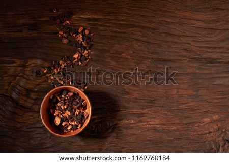 cup and dry tea leaves isolated on a wooden table
