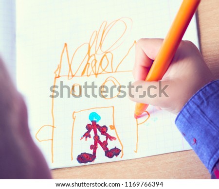 Boy is painting a picture. A beautiful child with felt-tip pens sits at the table and is engaged in creativity and art. Drawing in kindergarten, school.
