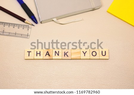 THANK YOU word written in wooden blocks on brown background. office desk with vintage concept. top view copy space.