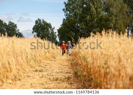 Little boy and girl on a wheat field in the sunlight running, playing enjoying nature. Kid Raising over field and sunset sky background. Children  environment concept