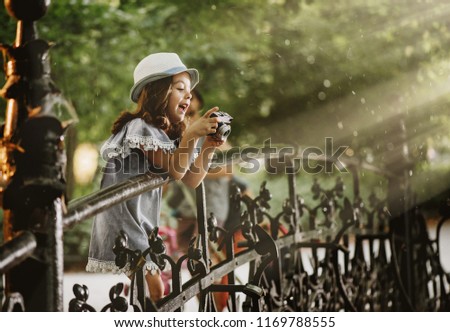 Little girl playing with camera in a park