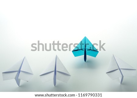 Business leadership concept with blue paper plane leading among white.