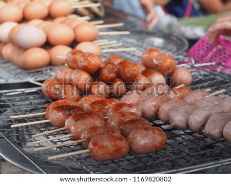 Selective focus picture of fermented sausages and blurred background of grilled eggs grill on charcoal stove.