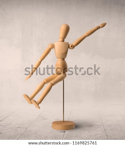Wooden mannequin posed in front of a greyish background