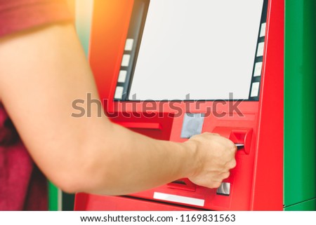 Man hand inserting debit or credit card to withdraw money with blank white screen ATM machine. Selective focus on hand with credit card using Automatic Teller Machine. Banking and financial concept.