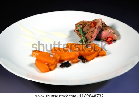 Tender grilled pieces of meat with carrot and cream on a white plate with isolated background. Roasted rack of lamb. 