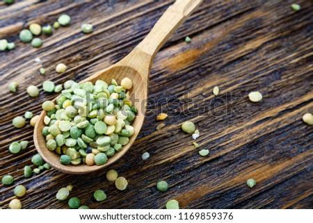 green dry peas in a wooden spoon on a wooden table

