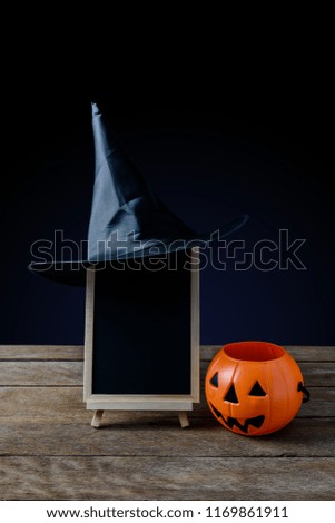 Halloween background. chalkboard on the stand, Witch hat with Halloween Pumpkins on wooden floor and black background