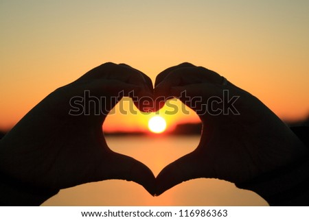 Hands make heart at sunset