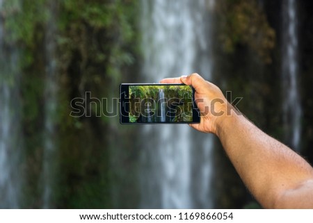 Taking picture of waterfall lansdcape with smart phone.