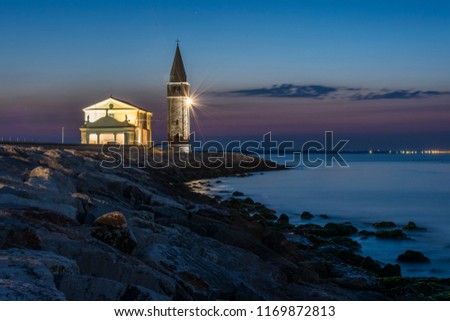 Enlightened church and tower "Santuario della Madonna dell'Angelo" in the town of Caorle on the coast at night. Royalty-Free Stock Photo #1169872813