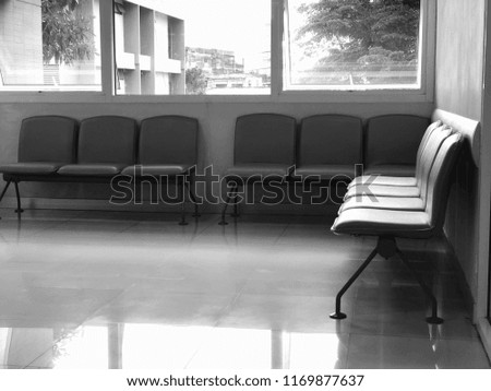 Black and white image, Row chair in dark room, has sunshine or a light through from window into the inside.