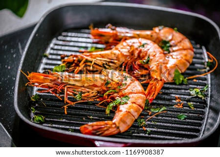 
Roasted tiger prawns in iron grilling pan with  lemon, black background, top view
