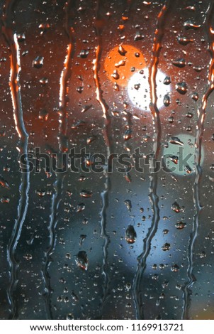 Drops of rain on wet glass window background. Street Bokeh Lights Out Of Focus. Vertical shot backdrop.
