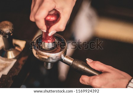 Barista presses ground coffee using tamper. Toned picture
