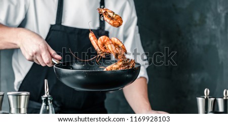 Chef cooking with Tiger prawn on dark background
