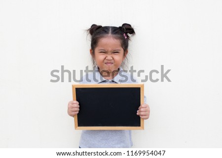 Portrait of a young Asian little girl holding a blank sign white blackboard on white wall background