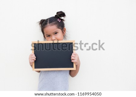 Portrait of a young Asian little girl holding a blank sign white blackboard on white wall background