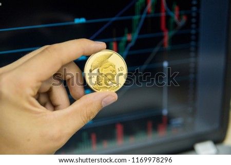 Male businessman hand holding titan bitcoin on a background of growth graph on a screen of laptop. Virtual money and Financial growth concept on chart background. Trading Mining of bitcoins.