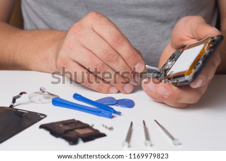 Repairman fixing disassembled smartphone with special tools and screwdrivers. concept of electronics repair devices