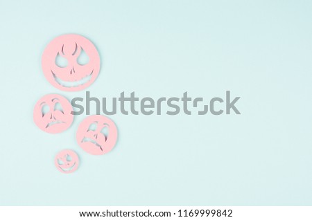 Halloween background - pink spooky faces emoji of cut paper on pastel trendy blue color.