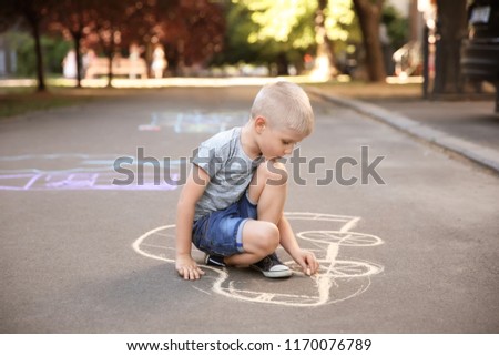 Little child drawing car with chalk on asphalt