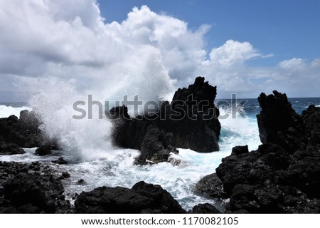 Large wave hitting a rocks creating a powerful splash going up into the sky.