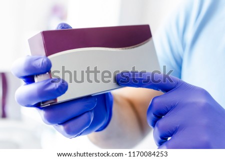 Close up of male dentist holding small medicine box in hands, with space for text.
