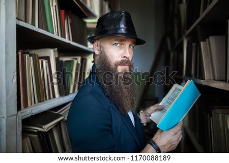 Stylish bearded man with book in library. education, university concept