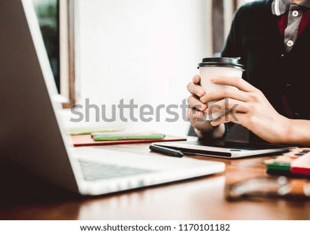 Website designer working digital tablet and computer laptop with smart phone and graphics design diagram in cafe.