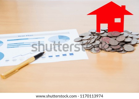 House Model And Stack Of Coins On Desk