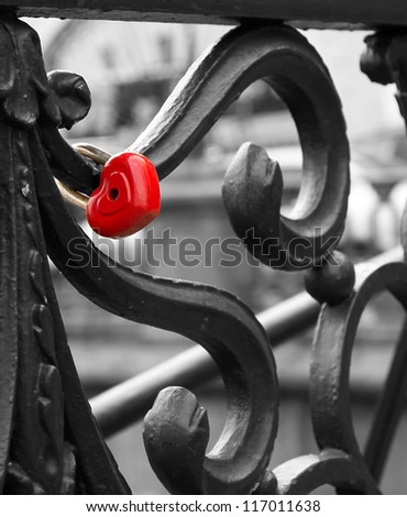 Romantic scene, heart lock attached to the bridge. Wedding tradition. Colored heart on black-and-white image. Wedding.