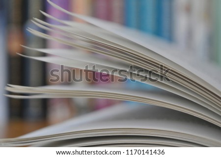 Close up pages from a book with other books in the background.