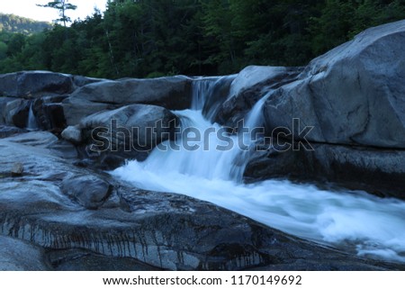 river running over rocks with waterfalls in early morning with smooth water