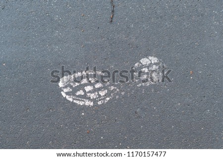 painted footprint on a wet grey asphalt