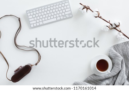 Top view of desk fo photographer with vintage camera, tea, warm blanket on white background. Flat lay with copy space.