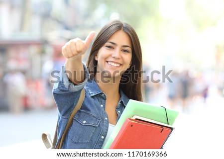Happy student posing with thumbs up looking at you in the street Royalty-Free Stock Photo #1170169366