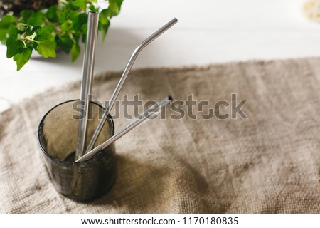 eco natural metallic straws in green glass on rustic background with greenery. sustainable lifestyle concept. zero waste, plastic free items. stop plastic pollution. Royalty-Free Stock Photo #1170180835