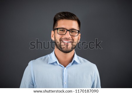 Handsome man standing over dark grey background and looking on camera. Portrait man concept.