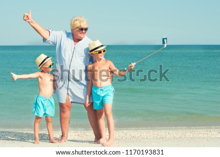 Grandmother with her grandchildren are resting on the sea, they are make a selfie on the beach.