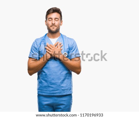 Young handsome doctor surgeon man over isolated background smiling with hands on chest with closed eyes and grateful gesture on face. Health concept.