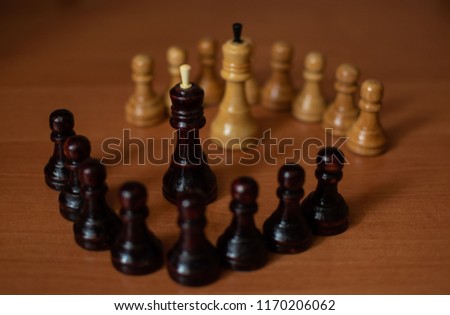 Pawns headed their kings from a black and white chess set. Two groups of chess pieces opposite each other.
