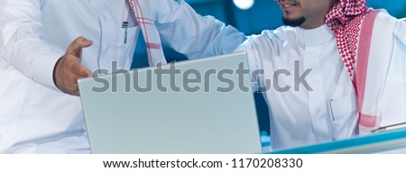 Two middle eastern businessmen at desk working on a laptop Royalty-Free Stock Photo #1170208330